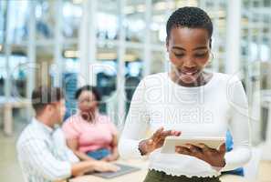 Keep it paperless, keep it productive. a young businesswoman using a digital tablet during a team meeting in a modern office.