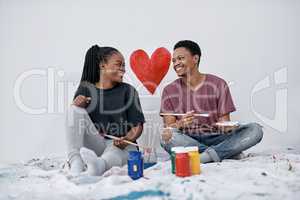 Love is at the heart of a happy home. a young couple painting a heart on a wall.