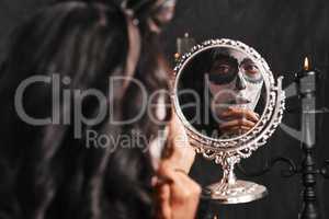 Halloween has arrived. an attractive young woman dressed in her Mexican-style halloween costume looking in a mirror.