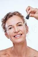 A face serum might be the answer. a mature woman posing with a serum dropper against her face.