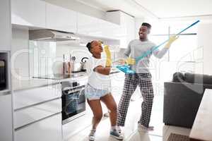 Nothing makes a marriage sparkle like good, clean fun. a happy young couple having fun while cleaning the kitchen at home.