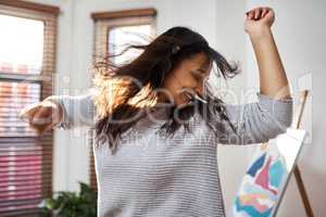 Happiness is dancing like crazy to your favourite song. a young woman dancing while listening to music at home.