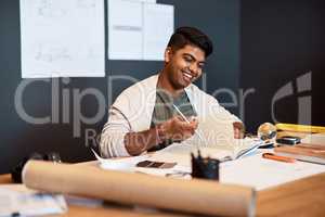 The home of contemporary architectural design. a young architect writing in a notebook at his desk in a modern office.