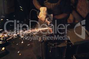 The steel industry is burning up. a man using an angle grinder while working at a foundry.