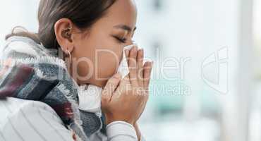 Remember when it used to be just the flu. a young businesswoman blowing her nose in a modern office.