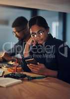 Your product will be ready for pick up tomorrow morning. a young technician using a smartphone while repairing computer hardware.