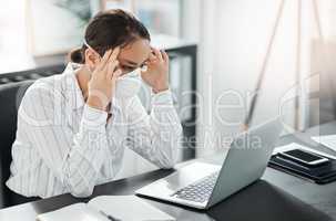 Unstable times lead to an increase in stress. a masked young businesswoman looking stressed while working at her desk in a modern office.