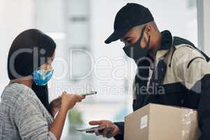 Contactless pay helps keep things under control. a masked young man and woman using smartphones during a home delivery.