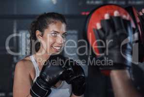 A great way to enhance your endurance. a young woman practicing with her coach at a boxing gym.