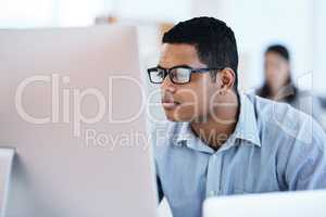 Nobody manages an IT network like he does. a young businessman using a computer in a modern office.