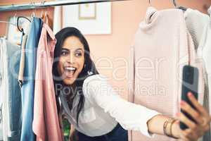 My wardrobe gets a lot of likes. a woman sticking her head in between items on a clothing rail while taking a selfie.