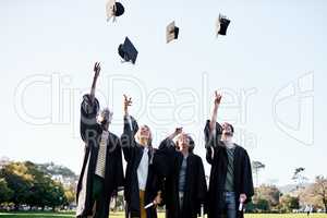 Thrilled about their new milestone. a group of students throwing their hats in the air on graduation day.