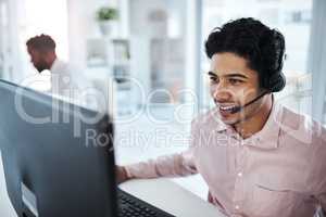 He knows what to say to make all the sales. a young call centre agent working on a computer in an office.