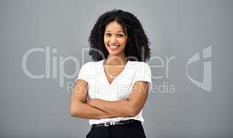 Confidence keeps you ahead of the game. Studio shot of a confident young businesswoman standing against a gray background.