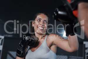 A total body workout that blasts calories. a young woman practicing with her coach at a boxing gym.