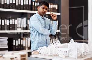 Laying the groundwork for a successful project. a young architect designing a building model in a modern office.
