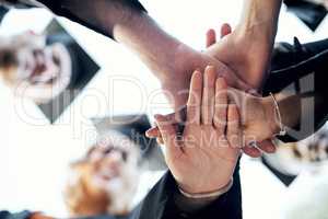 Heres to our bright future. Low angle shot of a group of students holding their hands together in a huddle on graduation day.
