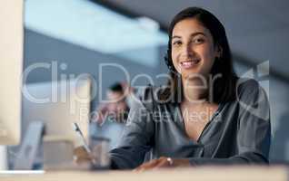 Build your client relationships, build your revenue. a young woman using a headset and computer late at night in a modern office.