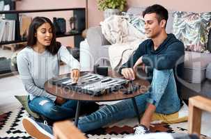 The healthy kind of game playing. a young couple playing a game of backgammon at home.