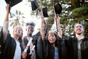 Education is the key to unlock the golden door of freedom. Portrait of a group of students holding raising hats in celebration on graduation day.