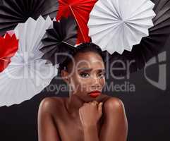 Stunning style gone global. Studio shot of a beautiful young woman posing with a origami fans against a black background.