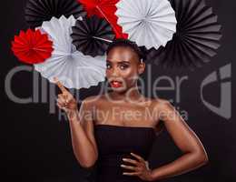 The more cultures, the more beautiful the world. Studio shot of a beautiful young woman posing with a origami fans against a black background.