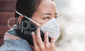 During this pandemic, technology really kept our relationships strong. a young woman wearing a mask while talking on the phone on the balcony at home.