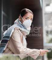 Social distancing doesnt mean social isolation. a young woman wearing a mask and using a smartphone on the balcony at home.