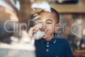 Water keeps me healthy. a young boy drinking a glass of water at home.