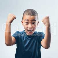 Growing up with a strong self esteem. Studio shot of a cute little boy flexing his muscles against a grey background.