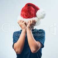 Christmas is cancelled. Studio shot of a cute little boy covering his head with a Santa hat against a grey background.