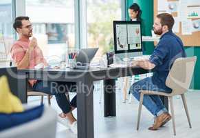 The team thats owning the design game. two young businessmen using their computers in a modern office.