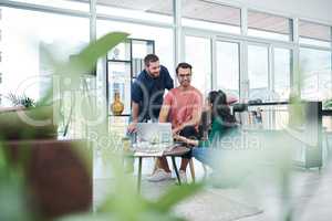 The headquarters of the hottest tech talent in town. a group of young businesspeople using a laptop together in a modern office.