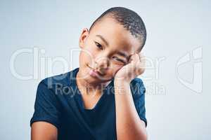 Somebody entertain me... Studio shot of a cute little boy looking bored against a grey background.