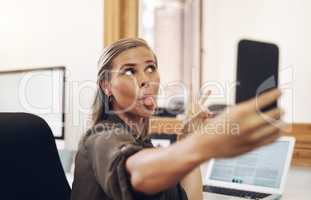 Just a bit of selfie silliness. a young businesswoman sticking out her tongue while taking selfies in an office.