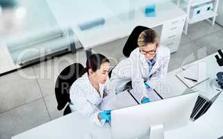 Putting their heads together on a new mystery. two scientists working together on a computer in a lab.