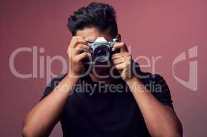 Look for the beauty in life. Studio shot of a young man holding up a camera.