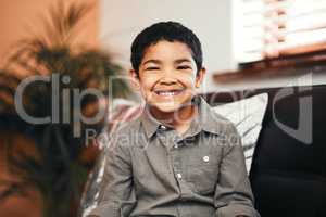 His little smile brightens up the whole room. Portrait of an adorable little boy relaxing on the sofa at home.