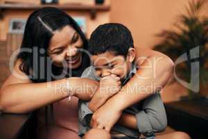 Mommy makes him giggle with her tickles. a mother tickling her little son at home.