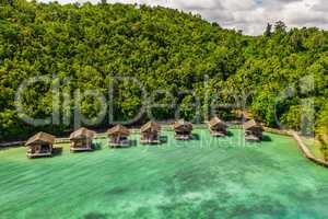 If youre looking to get away, this is the place. High angle shot of the overwater bungalows along the coast of the Raja Ampat Islands in Indonesia.