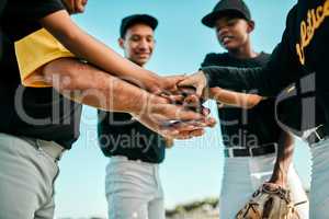 No one player can dominate the game. a team of young baseball players joining their hands together in a huddle during a game.