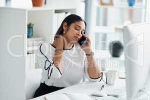 I cant be productive when my body feels like this. a young businesswoman rubbing her neck while talking on a cellphone in an office.