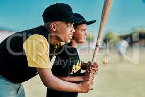 Baseball teaches patience and focus. a young baseball player showing a little boy how to play.