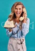 Keeping it old school. Studio shot of a young woman holding a telephone while wearing 80s clothing.