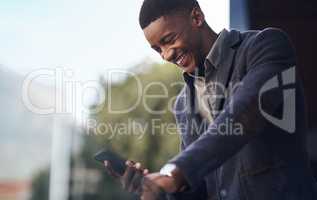Doing business with a smile on his face. a young businessman using a cellphone while standing on the balcony of an office.