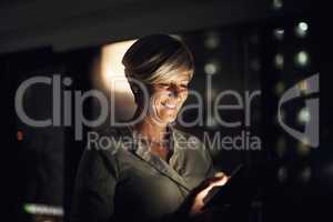 Analysing business operations right from her hands. a mature businesswoman using a digital tablet in an office at night.
