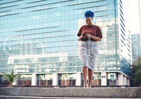 Its about time you stepped into the business spotlight. a young businesswoman using a smartphone against a city background.