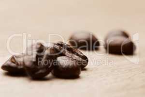 But first, coffee. Still life shot of coffee beans on a wooden countertop.