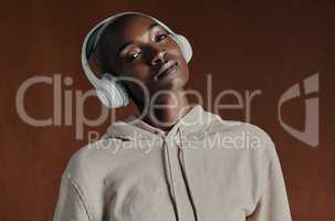 Dont follow the crowd, follow your own beat. Studio portrait of an attractive young woman wearing headphones and posing against a brown background.