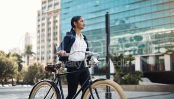 Ambition moves you forward. a young businesswoman traveling with a bicycle through the city.